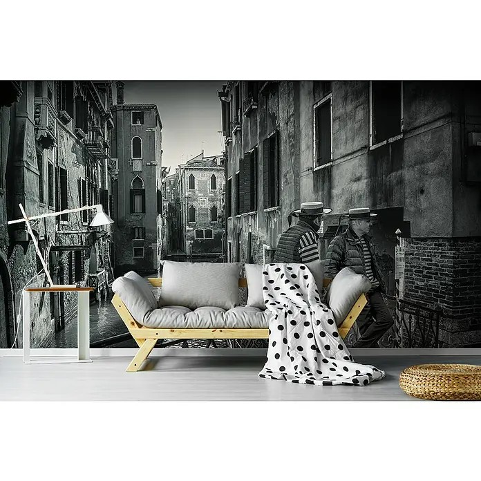 Papermoon Premium collection Fototapete Gondolieri - B x H: 200 x 149 cm, Vlies - Eine moderne Wohnzimmerdekoration mit einer Wandtapete von Venedig, einem hellen Holzsofa mit Kissen und einer schwarz-weiß gepunkteten Decke.