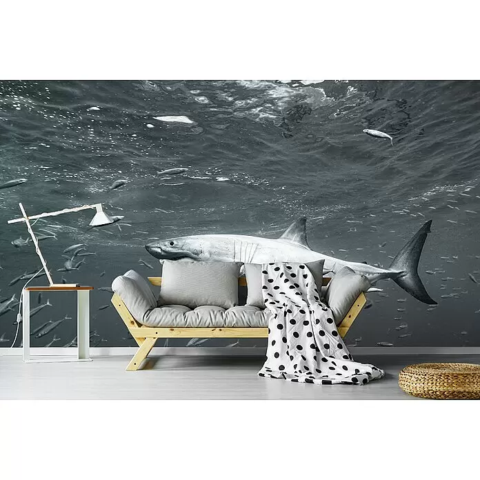 Papermoon Premium collection Fototapete An der Oberfläche - B x H: 300 x 223 cm, Vlies - Holzsofa mit grauen Kissen und gepunkteter Decke, Beistelltisch mit Holzlampe, geflochtener Hocker vor einem Unterwasser-Hai-Wandbild.