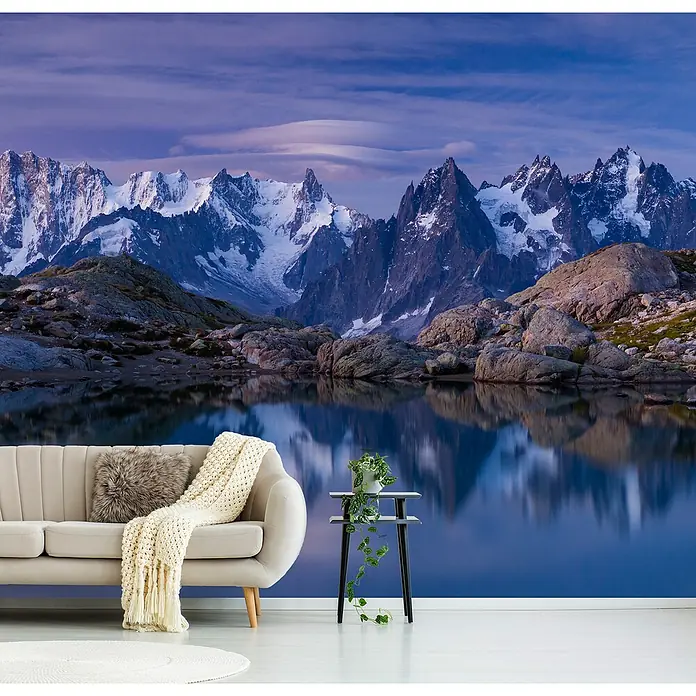 Papermoon Premium collection Fototapete Träume Morgengrauen - B x H: 450 x 280 cm, Vlies - Ein gemütliches Wohnzimmer mit einem stilvollen Sofa, einem Beistelltisch mit Pflanze und einer beeindruckenden Berglandschaft im Hintergrund.