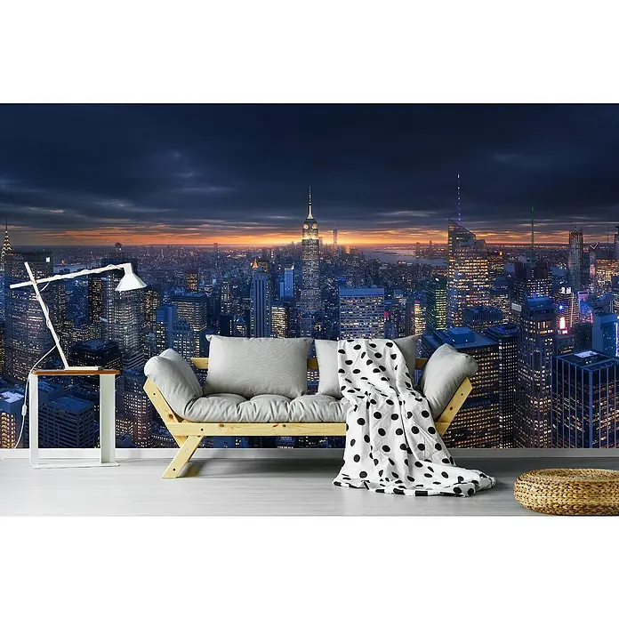 Papermoon Premium collection Fototapete Skyscraperview II - B x H: 450 x 280 cm, Vlies - Wohnzimmer mit einer Fototapete, die eine atemberaubende Skyline bei Nacht zeigt, einem hellen Sofa, einer Lampe und einem Hocker.
