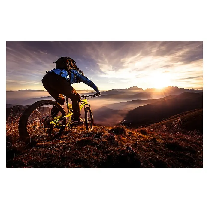 Papermoon Premium collection Fototapete Sunset Trail Ride - B x H: 350 x 260 cm, Vlies - Ein Mountainbiker mit Rucksack fährt auf einem gelben Mountainbike vor einer atemberaubenden Bergkulisse bei Sonnenuntergang.