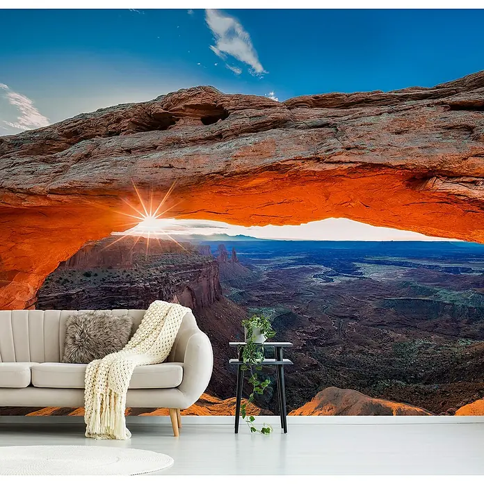 Papermoon Premium collection Fototapete Sunrise Mesa-Bogen - B x H: 350 x 260 cm, Vlies - Wohnzimmer-Innenraum mit Wandbild der Mesa Arch im Canyonlands Nationalpark, Utah. Beiges Sofa und Beistelltisch im Raum.