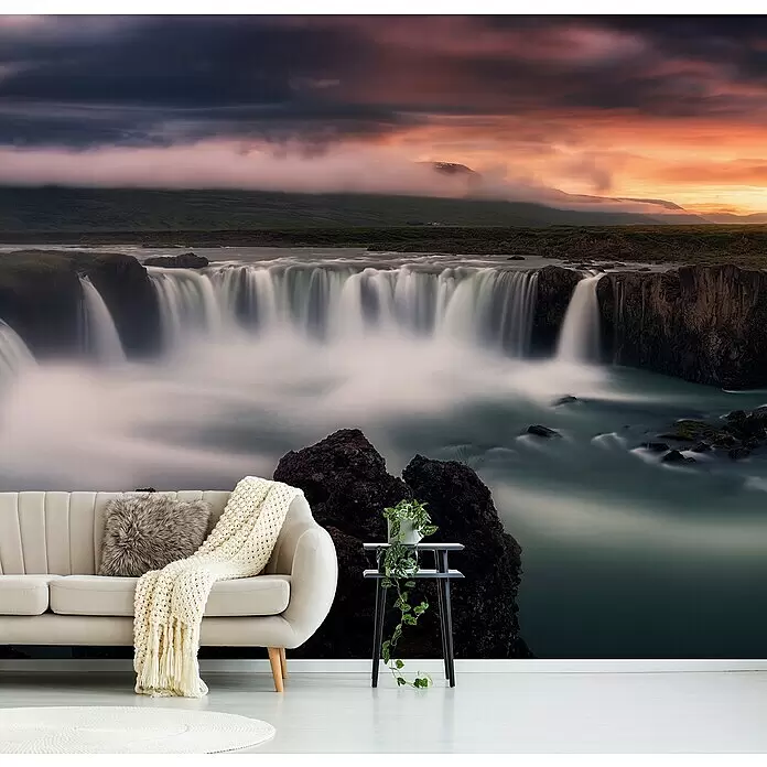 Papermoon Premium collection Fototapete Feuer und Wasser - B x H: 250 x 186 cm, Vlies - Wandtapete mit einem großen Wasserfall bei Sonnenuntergang, die ein Wohnzimmer mit Sofa und Beistelltisch schmückt.