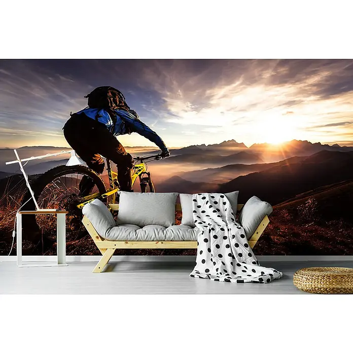 Papermoon Premium collection Fototapete Sunset Trail Ride - B x H: 350 x 260 cm, Vlies - Wandbild mit Bergmotiv und Mountainbike-Fahrer, kombiniert mit einem stilvollen Sofa, einem Beistelltisch und einem Hocker für ein modernes Wohnambiente.