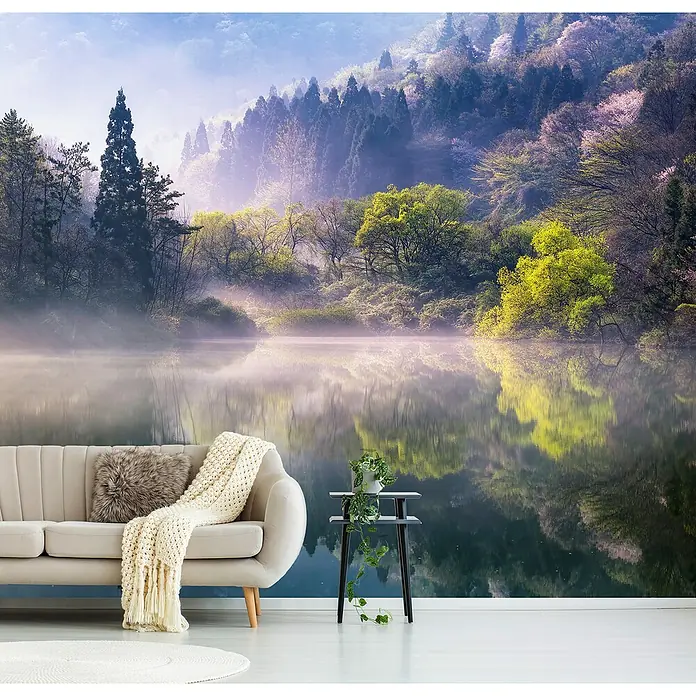 Papermoon Premium collection Fototapete Morgen ruhig - B x H: 250 x 186 cm, Vlies - Ein stilvolles Interieur mit einer Wandtapete, die eine ruhige See und einen bewaldeten Hügel zeigt, ergänzt durch ein beiges Sofa und einen Beistelltisch.