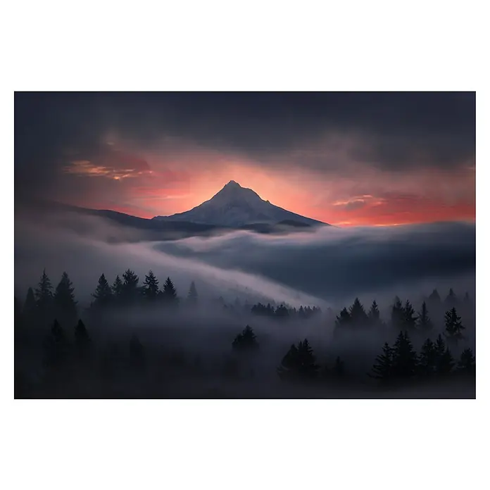Papermoon Premium collection Fototapete Durch das Fenster - B x H: 350 x 260 cm, Vlies - Malerische Landschaft mit Berggipfel, der aus Nebel und einem rot gefärbten Sonnenuntergang ragt, umrahmt von dunklen Tannen.
