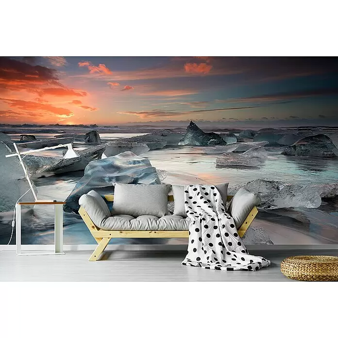 Papermoon Premium collection Fototapete Glacial Lagoon Beach - B x H: 450 x 280 cm, Vlies - Ein Wohnzimmer mit hellem Holzsofa, grauen Kissen, schwarz-weiß gepunkteter Decke, Beistelltisch und Hocker vor einer Eislandschaft.