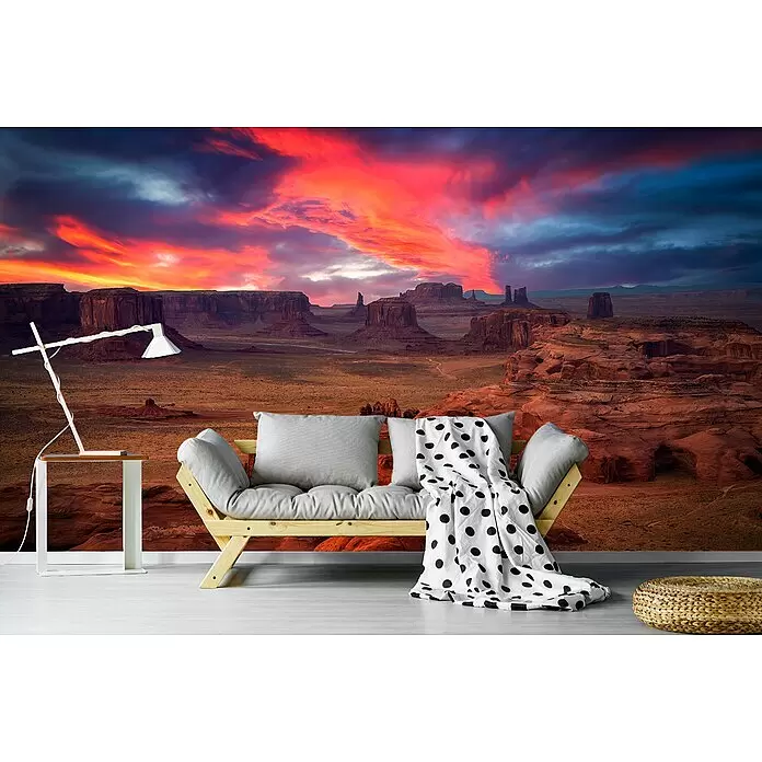 Papermoon Premium collection Fototapete Jagds Mesa - B x H: 300 x 223 cm, Vlies - Gemütlicher Raum mit Holzsofa, grauen Kissen, gepunkteter Decke, Lampe und Pouf, vor lebhafter Monument Valley Sonnenuntergangs-Wandmalerei.