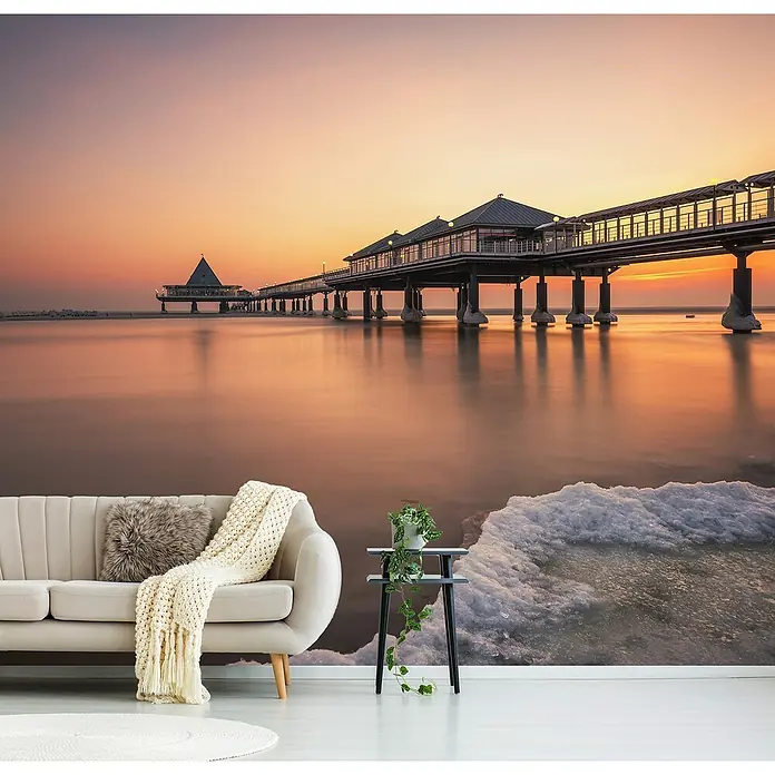 Papermoon Premium collection Fototapete Eiszeit - B x H: 250 x 186 cm, Vlies - Wandbild mit Seebrücke und Sofa. Das Bild zeigt eine entspannende Szene mit einem bequemen Sofa vor einer malerischen Seebrücke.