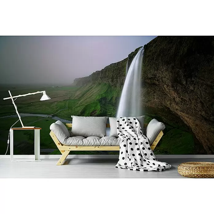 Papermoon Premium collection Fototapete Wasserfall Landschaft - B x H: 450 x 280 cm, Vlies - Helles Holzsofa mit grauen Kissen und Tupfendecke, ein weißer Beistelltisch mit Lampe und ein geflochtener Pouf in einem modernen Wohnraum.