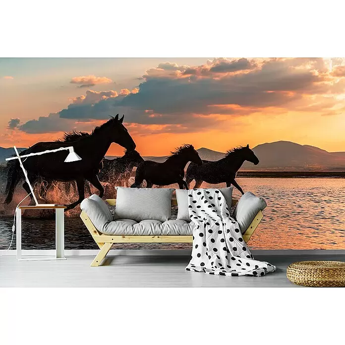 Papermoon Premium collection Fototapete Wasserpferde - B x H: 250 x 186 cm, Vlies - Holzsofa mit grauen Kissen und gepunkteter Decke, weißer Beistelltisch mit Lampe und geflochtener Pouf im Raum mit Pferdewandbild.