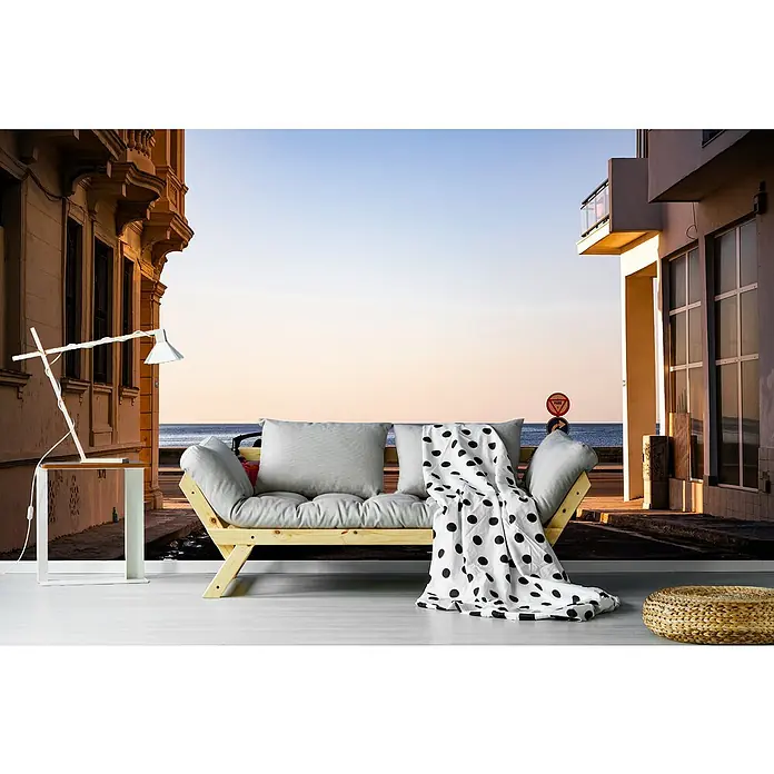 Papermoon Premium collection Fototapete Sunset Havanna - B x H: 250 x 186 cm, Vlies - Möbelarrangement mit einem hellen Holzsofa mit Polsterung, einer Stehlampe und einem Hocker vor einer Stadtszenerie.