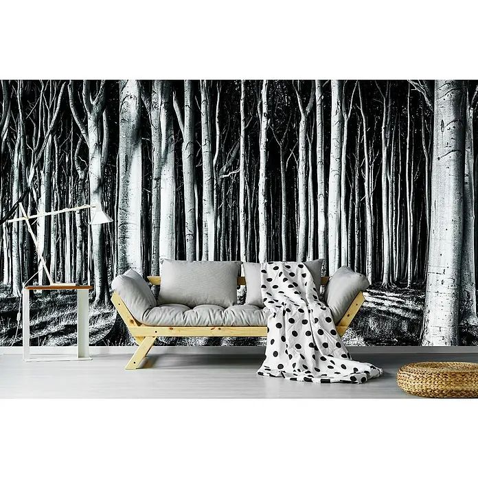 Papermoon Premium collection Fototapete Geisterwald - B x H: 300 x 223 cm, Vlies - Zimmer mit einem hellen Holzbettsofa, einer Stehlampe und einem runden Hocker. Die Tapete zeigt einen dichten Wald in Schwarzweiß.