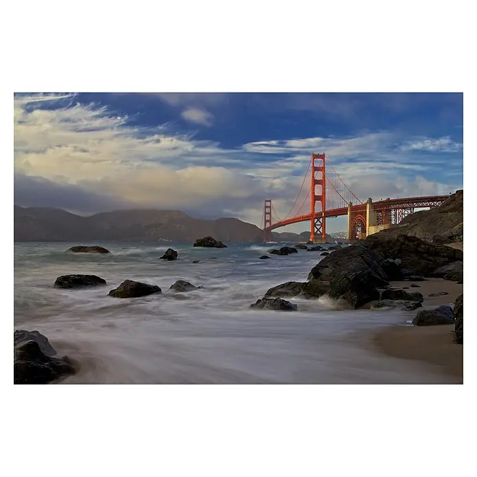 Papermoon Premium collection Fototapete Golden Gate Bridge - B x H: 450 x 280 cm, Vlies - Die Golden Gate Brücke in San Francisco, fotografiert vom Strand aus mit Felsen im Vordergrund und sanften Wellen.