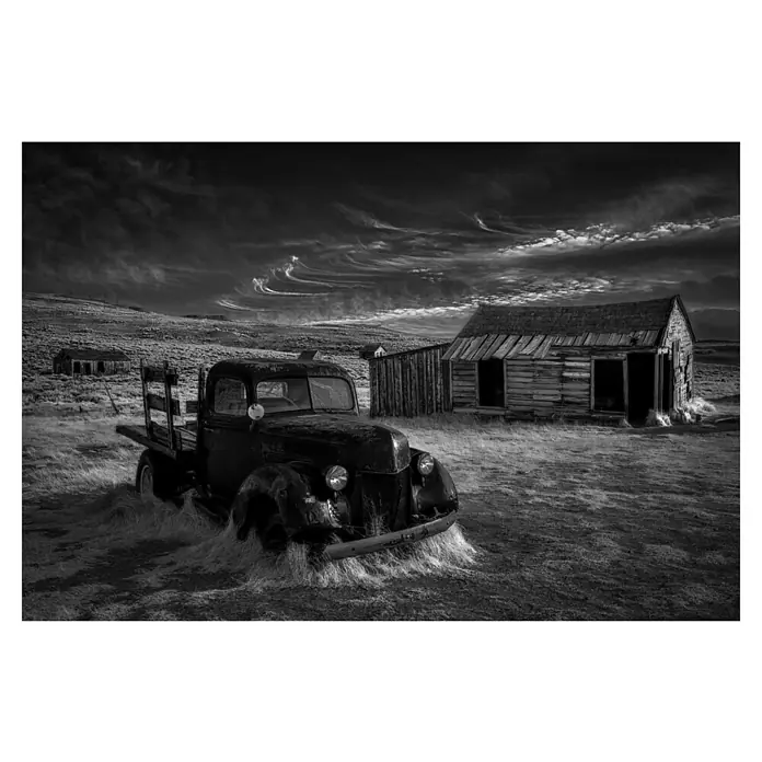 Papermoon Premium collection Fototapete Kein Gold mehr - B x H: 350 x 260 cm, Vlies - Verlassener Oldtimer-Truck in Schwarzweiß, umgeben von einer verfallenen Landschaft und dramatischem Himmel. Die Szene strahlt eine melancholische Atmosphäre aus.