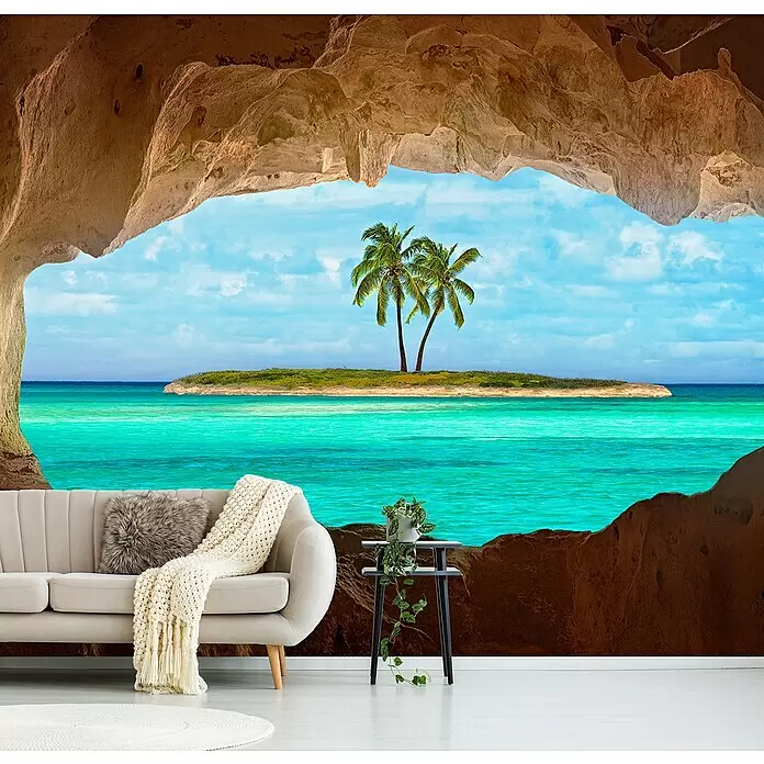 Papermoon Premium collection Fototapete Paradies - B x H: 250 x 186 cm, Vlies - Wandbild einer Höhlenöffnung zu einer tropischen Insel mit Palmen und türkisem Meer, einem beigen Sofa und Beistelltisch im Vordergrund.