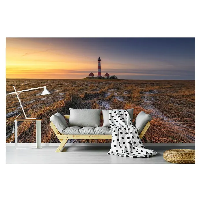 Papermoon Premium collection Fototapete Westerheversand - B x H: 250 x 186 cm, Vlies - Wohnzimmer-Szene mit Sofa, Stehlampe und Hocker vor einer beeindruckenden Leuchtturm-Tapete, die eine gemütliche Atmosphäre schafft.