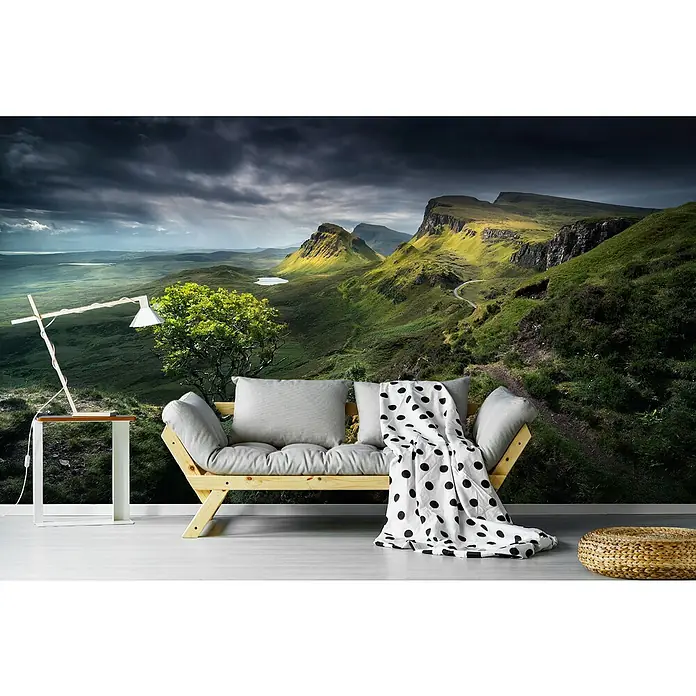 Papermoon Premium collection Fototapete Quirlaing - B x H: 250 x 186 cm, Vlies - Wohnzimmer mit Holzbettsofa, Kissen und gepunkteter Decke vor einer dramatischen Landschaftstapete.
