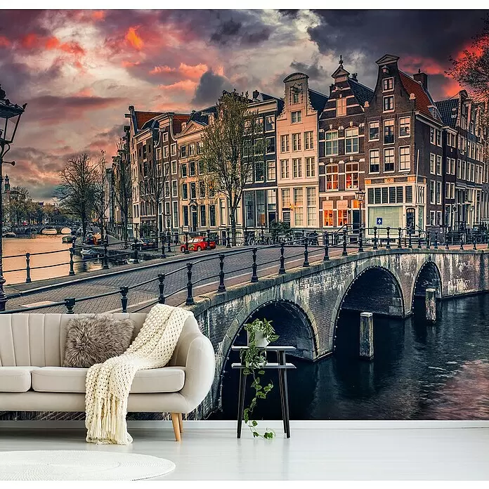 Papermoon Premium collection Fototapete Brücke in Amsterdam - B x H: 350 x 260 cm, Vlies - Wandbild mit einer Amsterdamer Grachtenszene, historischen Gebäuden und Brücken unter dramatischem Himmel, als lebendige Kulisse in einem modernen Wohnzimmer.