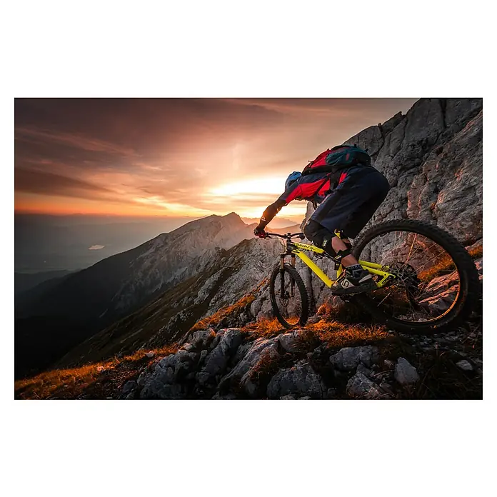 Papermoon Premium collection Fototapete Goldstunde Alpenfahrt BMX Fahrrad - B x H: 350 x 260 cm, Vlies - Ein Mountainbiker fährt mit einem gelben Mountainbike auf einem felsigen Bergpfad bei Sonnenuntergang.