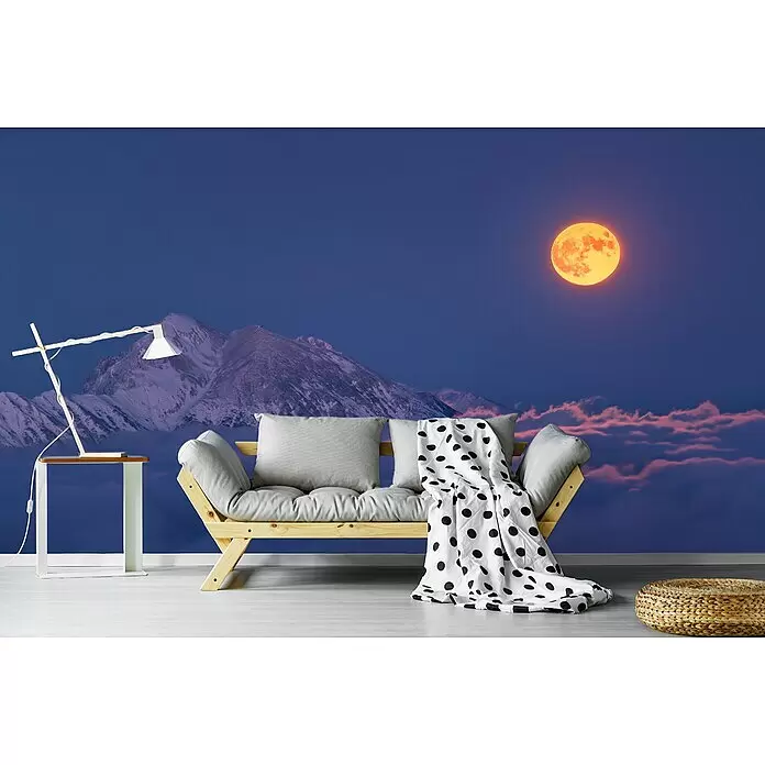 Papermoon Premium collection Fototapete Mond über den Wolken - B x H: 350 x 260 cm, Vlies - Holzsofa mit hellgrauen Kissen und weißer gepunkteter Decke vor einer Bergwandmalerei mit Vollmond.