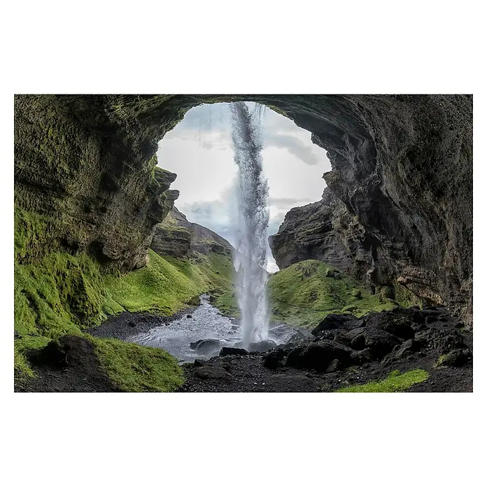Papermoon Premium collection Fototapete Versteinerter Wasserfall - B x H: 250 x 186 cm, Vlies - Ein atemberaubender Blick aus einer Höhle auf einen Wasserfall, umgeben von grüner Vegetation und dunklem Gestein. Die Szene fängt die natürliche Schönheit Islands ein.