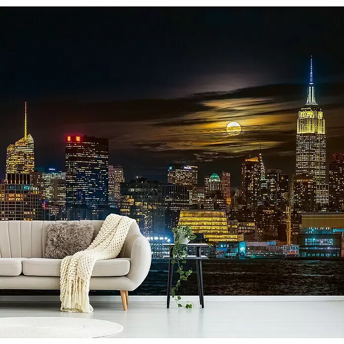 Papermoon Premium collection Fototapete New York City - B x H: 250 x 186 cm, Vlies - Großes Wandbild mit einer lebendigen New Yorker Skyline bei Nacht und einem hellen Vollmond, hinter einem modernen beigen Sofa und Beistelltisch.