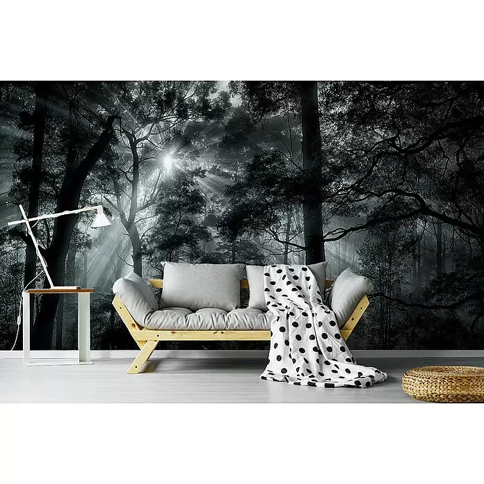 Papermoon Premium collection Fototapete Primärwald - B x H: 200 x 149 cm, Vlies - Helles Holzsofa mit grauen Kissen und gepunkteter Decke in einem Zimmer mit Wald-Wandbild, Tisch, Lampe und geflochtenem Pouf.