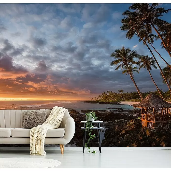 Papermoon Premium collection Fototapete Rückkehr zum Paradies - B x H: 250 x 186 cm, Vlies - Eine Wandtapete mit tropischem Strandsonnenuntergang, Palmen und einer Hütte, in einem modernen Wohnzimmer mit beigem Sofa.