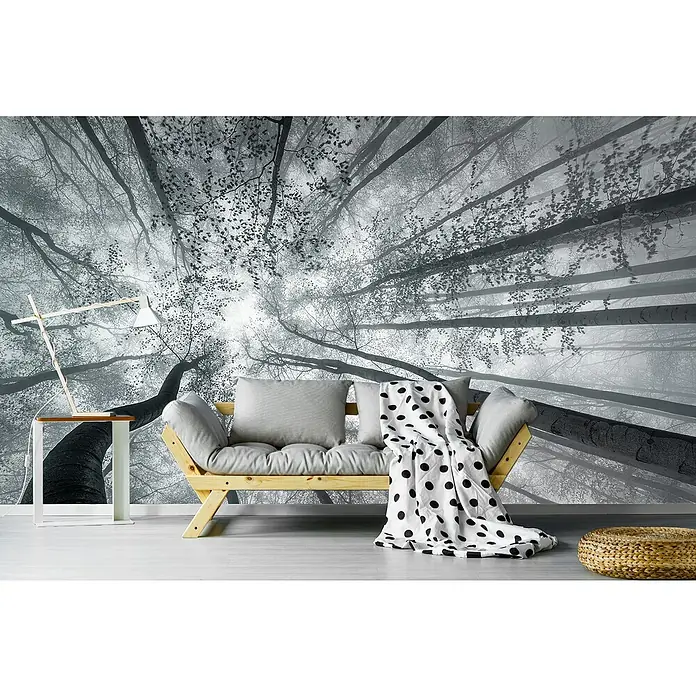 Papermoon Premium collection Fototapete Blick zu den Baumspitzen - B x H: 450 x 280 cm, Vlies - Wohnzimmer mit hellem Holzsofa, Polsterkissen, gepunkteter Decke, Lampe und Beistelltisch, vor einer Fototapete mit Baummotiv.