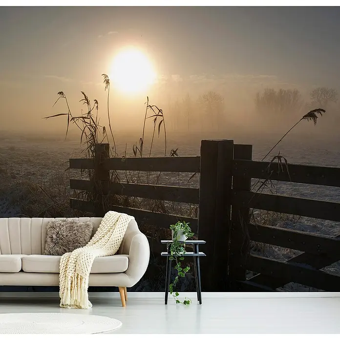 Papermoon Premium collection Fototapete Winterstimmung - B x H: 300 x 223 cm, Vlies - Das helle Wohnzimmer mit einer Landschaftstapete mit einem Holzzaun bei Sonnenaufgang, einem Sofa und einem Beistelltisch ist gemütlich.