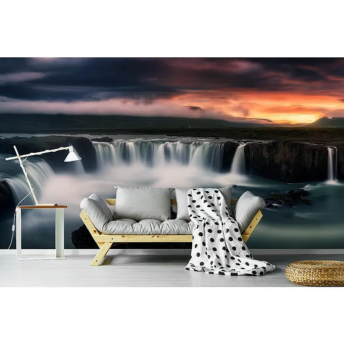 Papermoon Premium collection Fototapete Feuer und Wasser - B x H: 250 x 186 cm, Vlies - Wohnzimmer mit bequemer Couch, Kissen und Tagesdecke, ergänzt durch einen stilvollen Tisch und eine Lampe vor einer malerischen Wasserfalltapete.