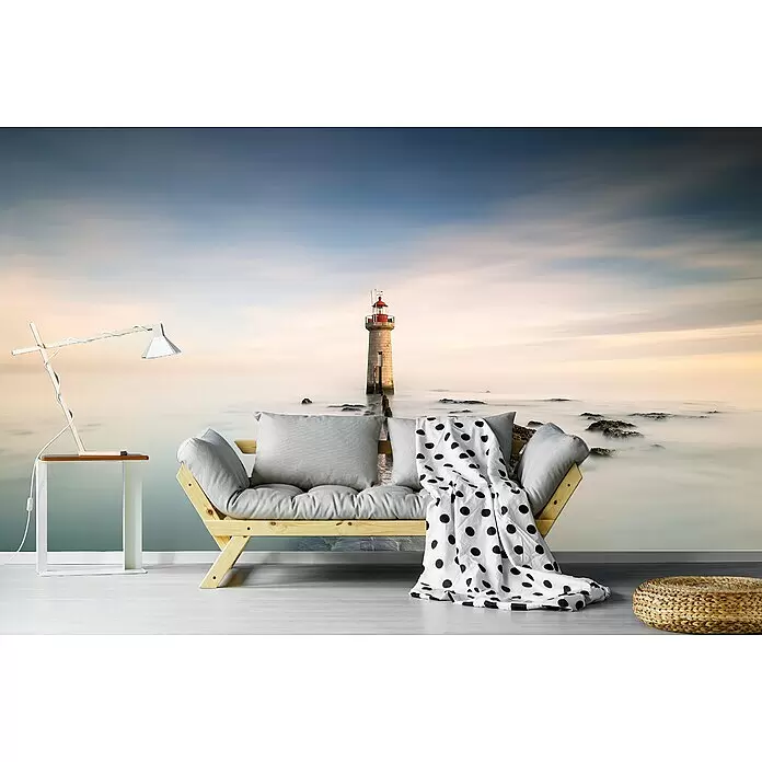 Papermoon Premium collection Fototapete Leuchtturm - B x H: 250 x 186 cm, Vlies - Helles Holzsofa mit grauen Kissen und gepunkteter Decke in einem Wohnraum, dazu eine weiße Lampe und Strohpouf.