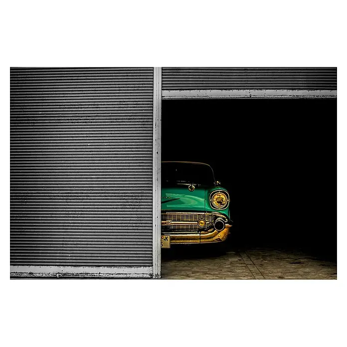 Papermoon Premium collection Fototapete Versteckte Schönheit - B x H: 350 x 260 cm, Vlies - Ein klassischer türkisfarbener Oldtimer, teilweise sichtbar durch ein geöffnetes Garagentor, das die elegante Front und den goldenen Kühlergrill hervorhebt.