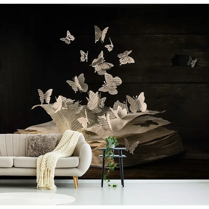 Papermoon Premium collection Fototapete Lepidopterologie - B x H: 400 x 260 cm, Vlies - Das Foto zeigt eine Wandtapete mit einem offenen Buch, aus dem Papier-Schmetterlinge fliegen, neben einem beigen Sofa und einem kleinen Beistelltisch.