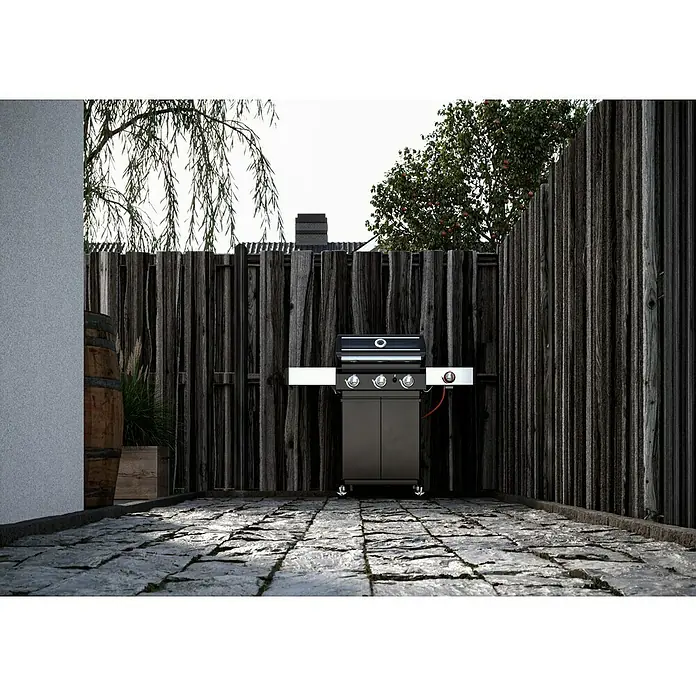 T & J Pfosten - 9 x 9 x 210 cm, Grün, Abgerundeter Pfostenkopf - Das Bild zeigt einen schwarzen Gasgrill mit silbernen Ablageflächen vor einem rustikalen Holzzaun in einem gepflasterten Außenbereich.
