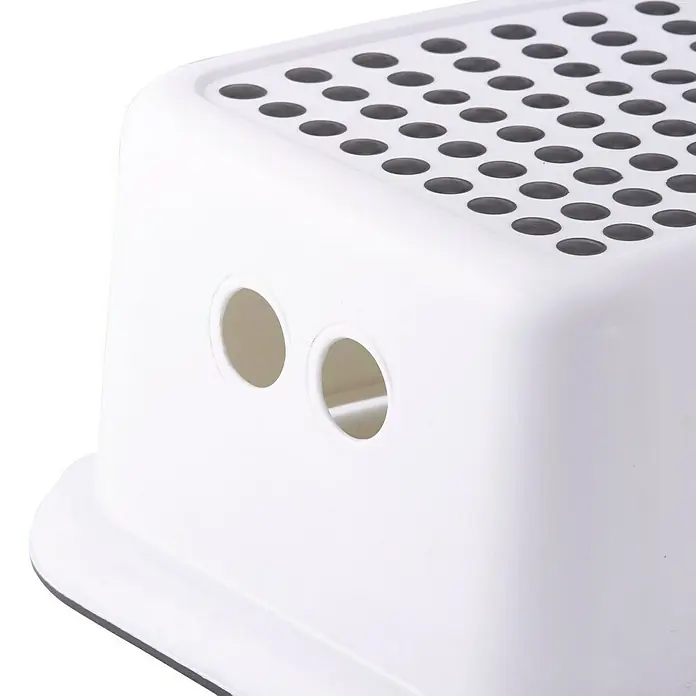 Escalón para baño - Altura: 24,5 cm, Blanco - Primer plano de un taburete blanco con agujeros texturizados en la superficie superior y agujeros redondos en el lateral.