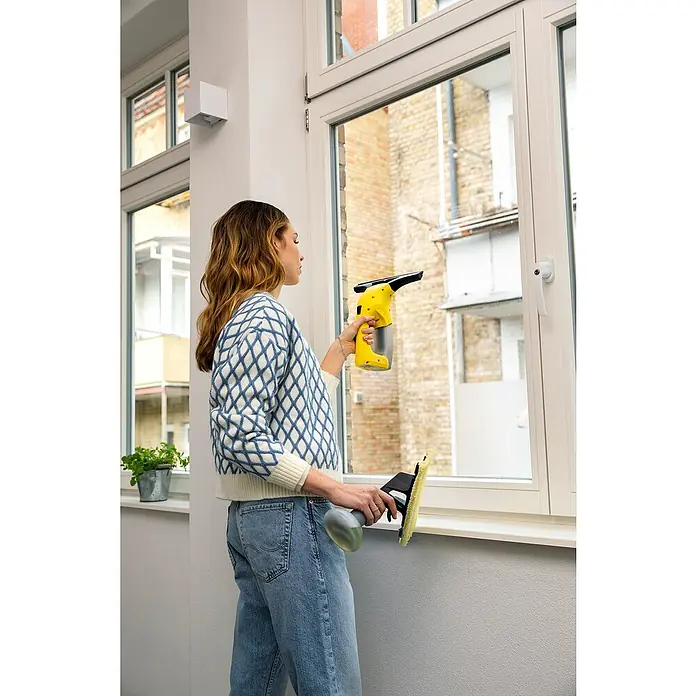 Kärcher Limpiadora de cristales de batería WV1 Plus - 1 batería, Volumen de recipiente: 0,1 l - Mujer limpiando ventanas con un aspirador de ventanas inalámbrico Kärcher WV 1 Plus amarillo y un juego de botellas rociadoras, para un acabado brillante.