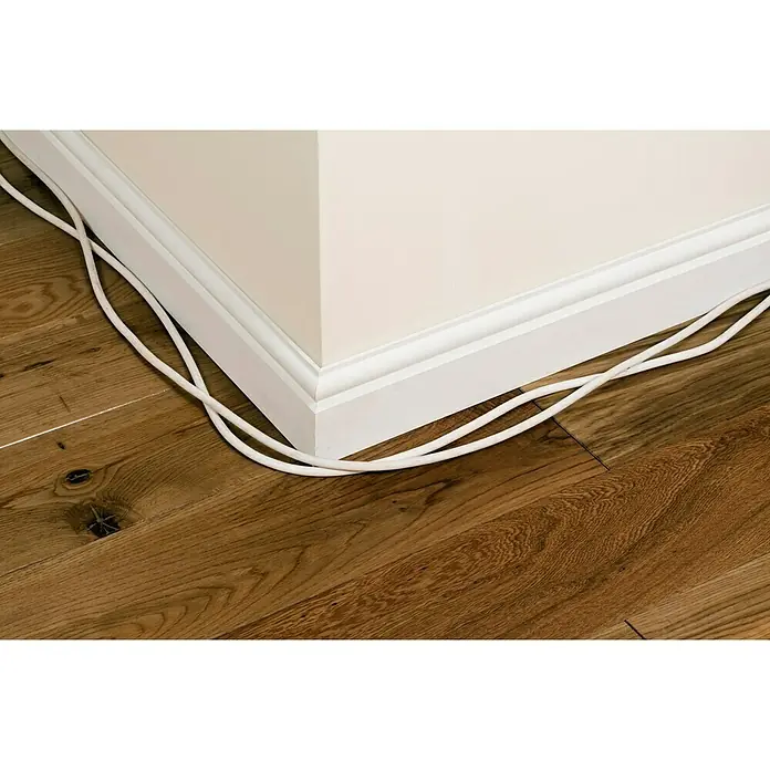 D-Line Kabelkanal Viertelrund - 1 m, 22 x 22 mm, Weiß - Weisses Kabel liegt entlang einer weissen Fussleiste auf einem Holzboden. Elegante Kabelführung, die sich harmonisch in den Raum einfügt.