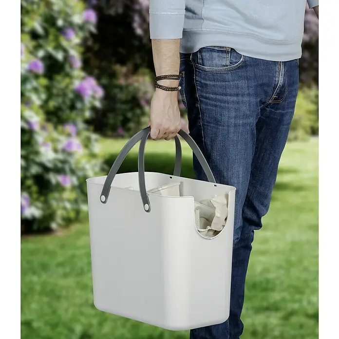 Rotho Albula Mülltrennsystem - 25 l, Kunststoff, Weiß - Eine Person trägt einen grauen Tragetaschen-Organizer für die Aufbewahrung. Ideal für Haushalt, Garten oder Büro und bietet zusätzlichen Stauraum.