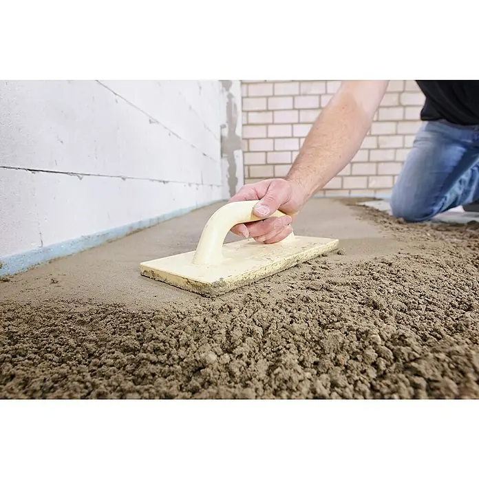 Quick-Mix Estrichbeton B03 - 40 kg - Ein Bauarbeiter glättet Estrich mit einer Estrichharke in einem Neubau, um einen ebenen Untergrund für Bodenbeläge zu schaffen.