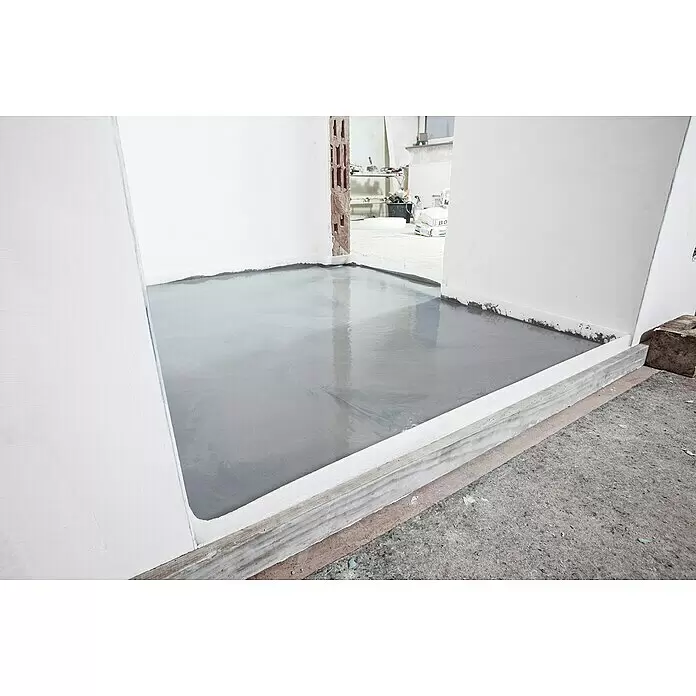 Quick-Mix Ausgleichsmasse Sicher+Plan XXL - 20 kg, Schichtdicke: 2 mm - 60 mm - Frisch vergossener, nasser grauer Nivellierboden in einem Raum mit weißem Dehnungsfugenband an den Wänden.