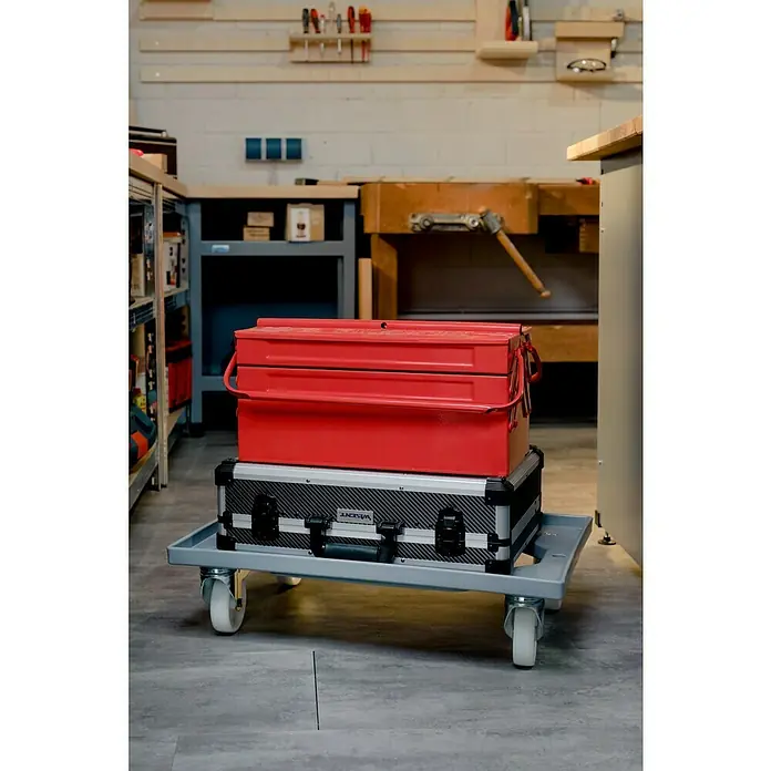 BAUHAUS Caja Euro + base con ruedas - 40 l, L x An x Al: 60 x 40 x 20 cm, 6 pzs. - Escena de taller con una caja de herramientas roja sobre una plataforma con ruedas. La caja de herramientas y la plataforma son los elementos centrales.