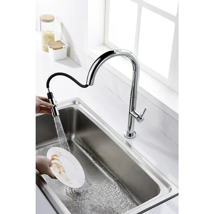 Imex Grifo de cocina extraíble Samoa - Cromo - Un elegante grifo de cocina extraíble se utiliza para enjuagar un plato en un fregadero de acero inoxidable para una limpieza fácil.