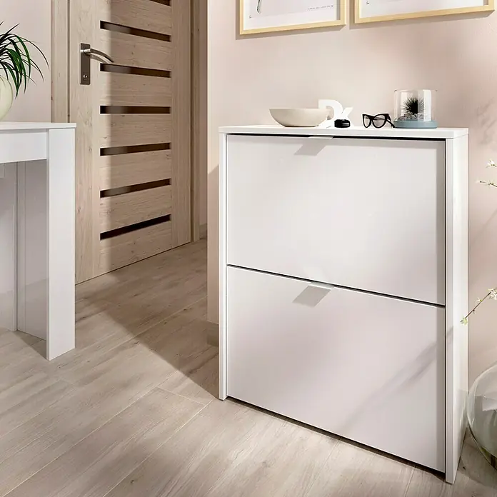 Dekit Zapatero Jazz - L x An x Al: 25 x 61 x 76 cm, Blanco - Imagen de un mueble zapatero blanco con dos compartimentos, colocado en el pasillo, proporcionando almacenamiento para zapatos.\n
