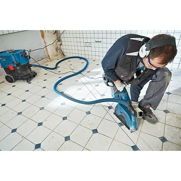 Bosch Professional Absaugvorrichtung - Passend für: Bosch Winkelschleifer GWS-Serie mit Ø 230 mm - Ein Handwerker benutzt eine Bosch Mauernutfräse mit Staubsauger für staubfreies Arbeiten, ideal für Renovierungsarbeiten.