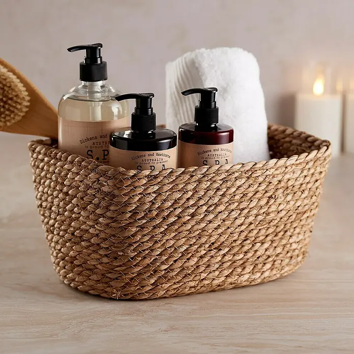 Cesta de junco - L x An x Al: 20 x 30 x 15 cm, Natural - Una cesta de mimbre llena de elementos esenciales para el baño como lociones, una toalla y un cepillo.
