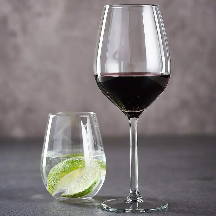 Set de copas y vasos - Vidrio, 8 pzs. - Una copa de vino tinto y un vaso de limonada sobre una mesa gris. Ambiente elegante para disfrutar y refrescarse en armoniosa combinación.