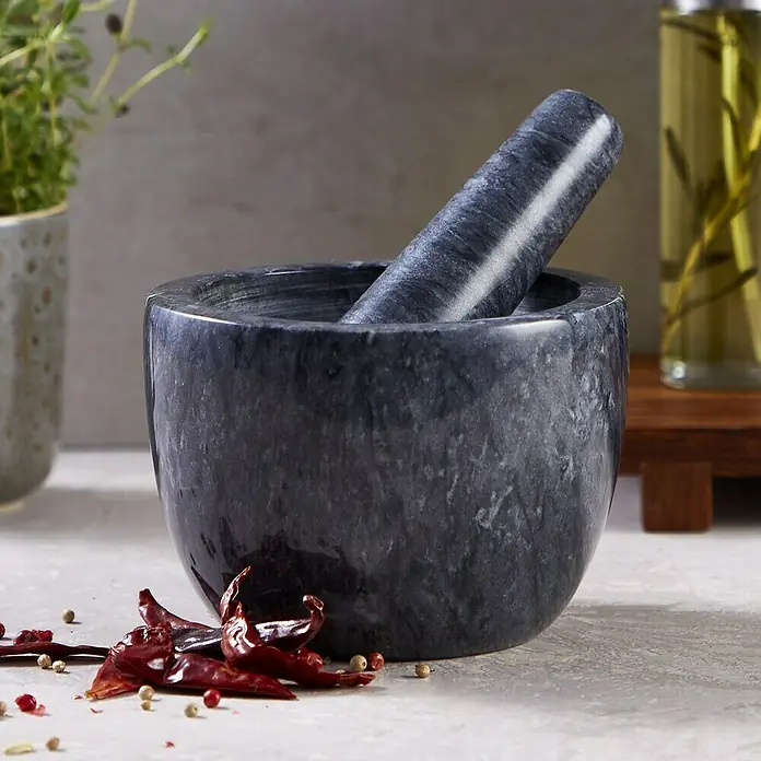 Mortero de cocina - Ø x Al: 12 x 9 cm, Piedra - Primer plano de un mortero gris con mano de mortero y chiles rojos en una encimera.