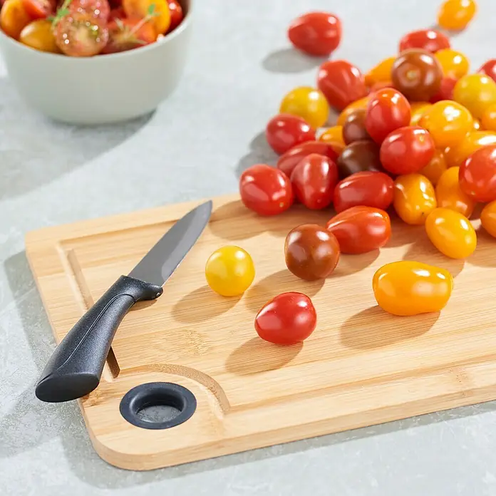 Tabla de cortar - 20 x 28 x 1 cm, Bambú - Primer plano de tomates cherry en una tabla de madera junto a un pequeño cuchillo de cocina.